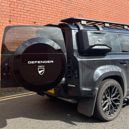 Land rover Defender With New Aquarius Manufacturing C mould Spare Wheel Cover, door open, red brck wall behind, sunny day